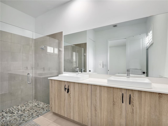 full bath featuring double vanity, a shower stall, tile patterned flooring, and a sink