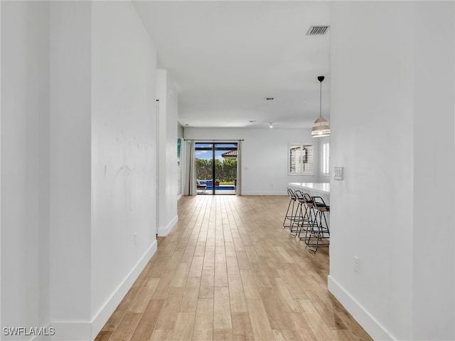 corridor featuring baseboards, visible vents, and light wood-style flooring