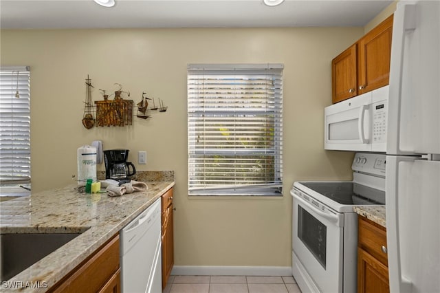 kitchen featuring light stone countertops, light tile patterned floors, and white appliances