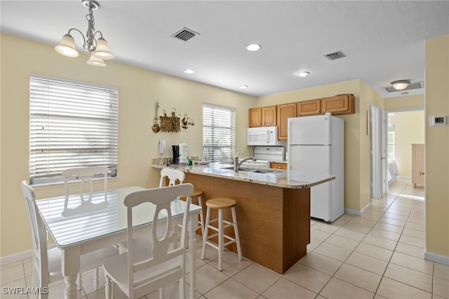 kitchen featuring light tile patterned flooring, light stone counters, kitchen peninsula, pendant lighting, and white appliances