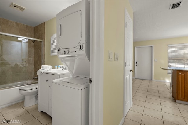 washroom with stacked washer and dryer and light tile patterned floors