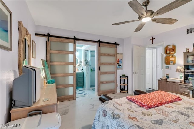 bedroom with a barn door, ceiling fan, and ensuite bath