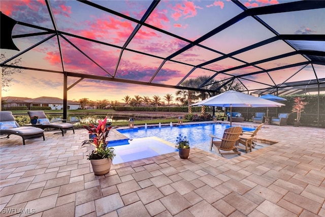 pool at dusk with pool water feature, a jacuzzi, glass enclosure, and a patio area