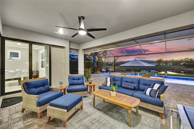 patio terrace at dusk featuring a lanai, an outdoor hangout area, and ceiling fan