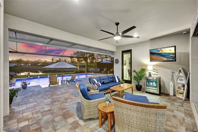 interior space with a water view, glass enclosure, ceiling fan, beverage cooler, and an outdoor hangout area