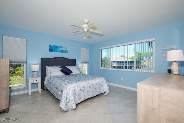 tiled bedroom with ceiling fan and multiple windows