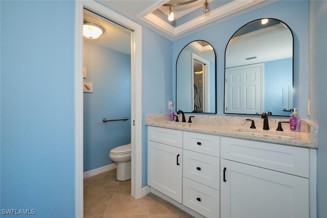 bathroom with tile patterned flooring, vanity, ornamental molding, a tray ceiling, and toilet