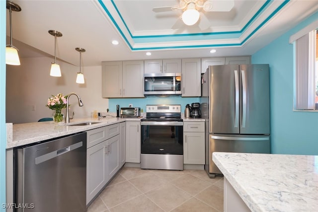 kitchen with stainless steel appliances, a raised ceiling, sink, and gray cabinetry