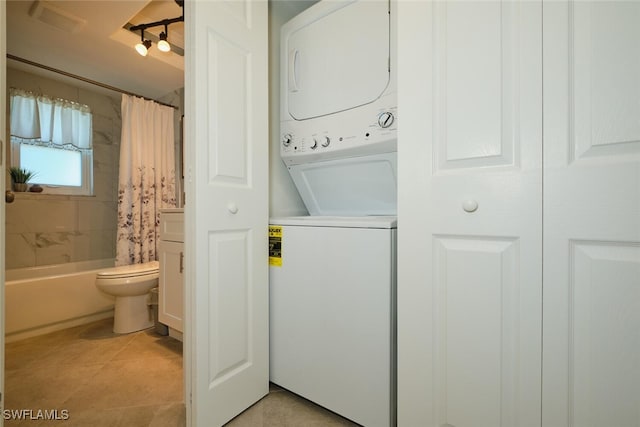 laundry area featuring light tile patterned floors and stacked washer and clothes dryer