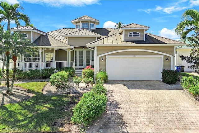 view of front of house with a garage, a porch, and french doors