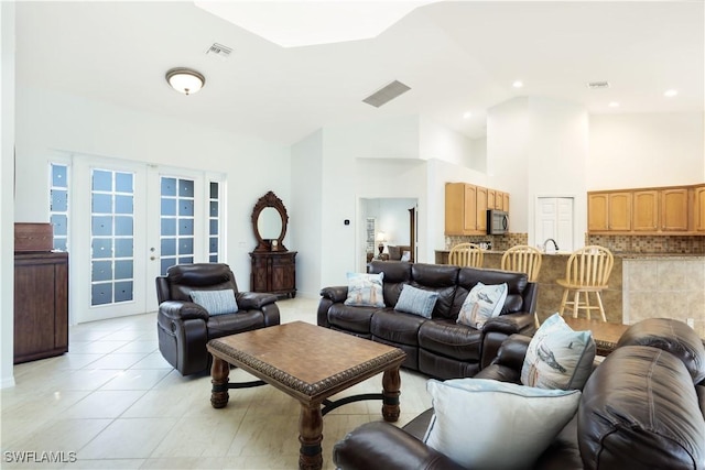 tiled living room with french doors and high vaulted ceiling