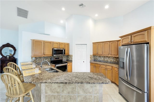 kitchen featuring appliances with stainless steel finishes, sink, a kitchen breakfast bar, light stone counters, and kitchen peninsula