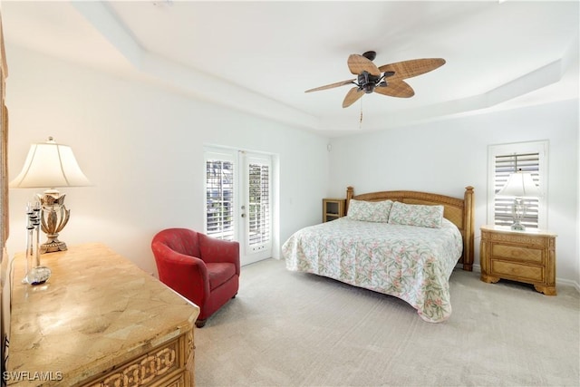 bedroom with light carpet, access to exterior, a raised ceiling, and ceiling fan