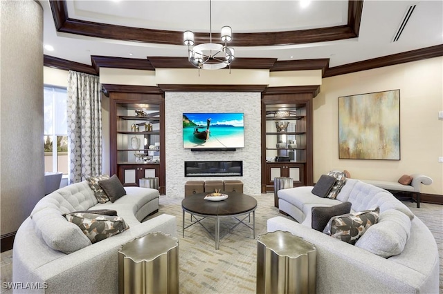 living room with crown molding, a chandelier, built in features, a fireplace, and hardwood / wood-style floors