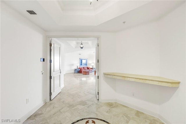 corridor with ornamental molding and a tray ceiling