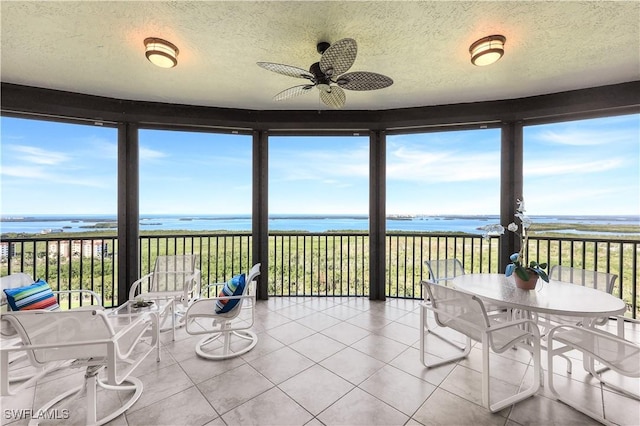 unfurnished sunroom featuring a water view, a wealth of natural light, and ceiling fan