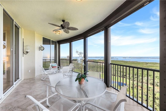 sunroom featuring a water view and ceiling fan