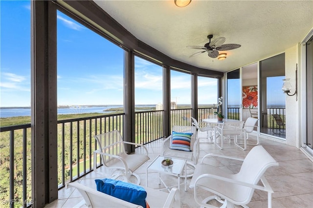 sunroom featuring a water view and ceiling fan