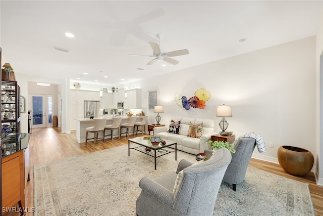 living room with ceiling fan and light hardwood / wood-style flooring