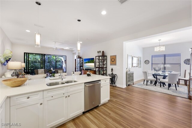 kitchen featuring pendant lighting, stainless steel dishwasher, white cabinetry, and sink