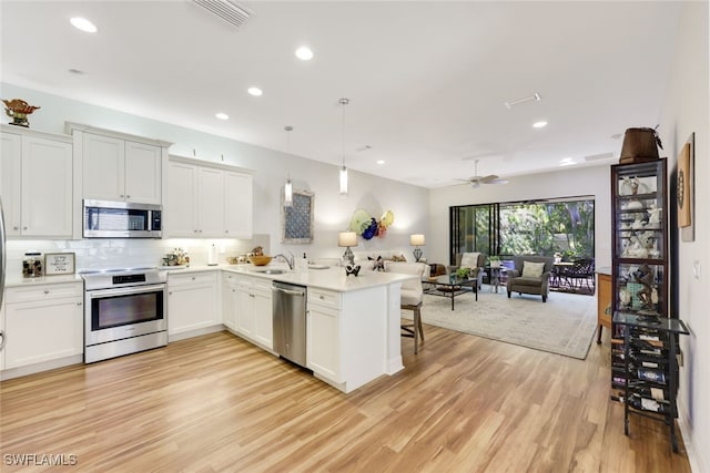 kitchen featuring white cabinetry, appliances with stainless steel finishes, pendant lighting, and kitchen peninsula