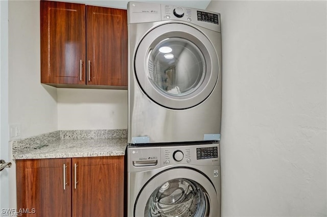 laundry area featuring cabinets and stacked washer / dryer