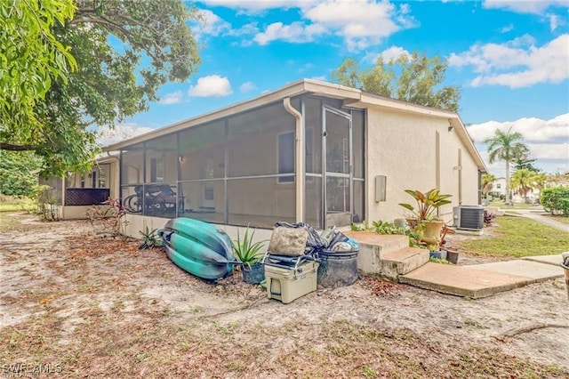 view of property exterior with cooling unit and glass enclosure