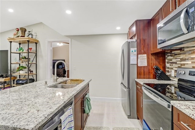 kitchen with sink, backsplash, light stone counters, stainless steel appliances, and light hardwood / wood-style flooring