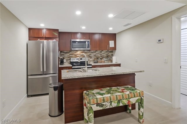 kitchen with tasteful backsplash, appliances with stainless steel finishes, sink, and a center island with sink