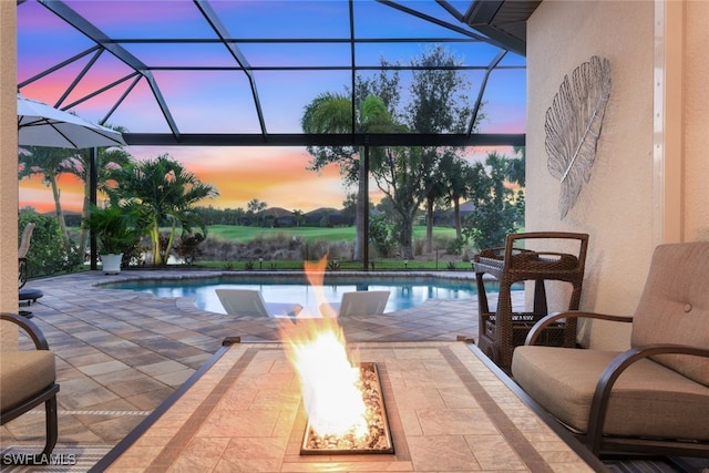 pool at dusk featuring a patio, a lanai, and a fire pit