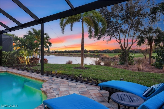 pool at dusk with a water view, a lawn, and a patio area