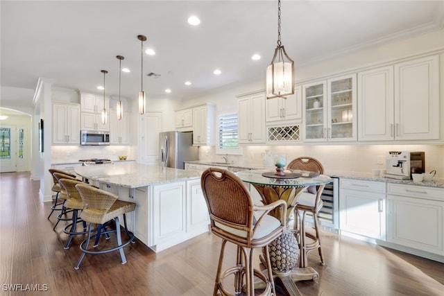 kitchen with pendant lighting, stainless steel appliances, a center island, and white cabinets