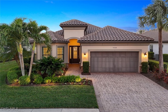 mediterranean / spanish-style house with a garage and a lawn