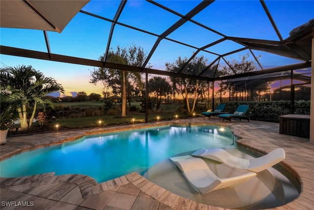 pool at dusk featuring a patio and glass enclosure