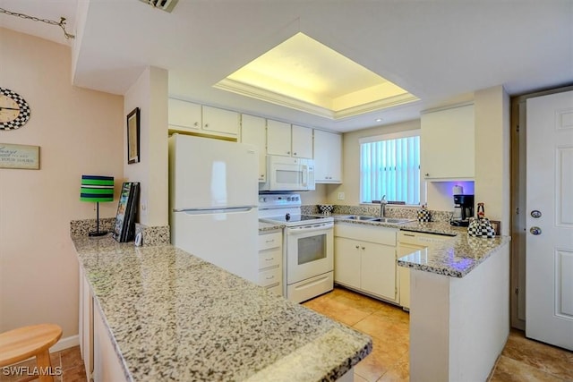 kitchen featuring sink, white appliances, a tray ceiling, light stone countertops, and kitchen peninsula