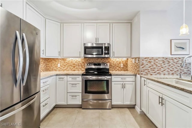 kitchen with sink, white cabinetry, pendant lighting, stainless steel appliances, and light stone countertops