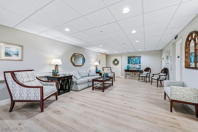 living room featuring a drop ceiling and light hardwood / wood-style flooring