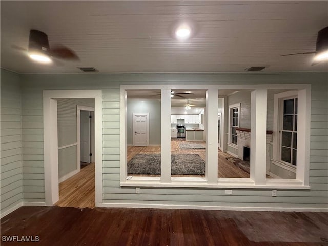 unfurnished room featuring a fireplace, wood-type flooring, and ceiling fan