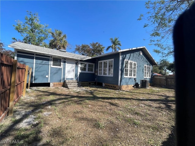 back of property with a yard and central AC