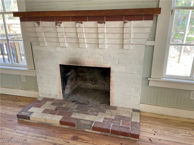 room details with wood-type flooring, wooden walls, and a brick fireplace