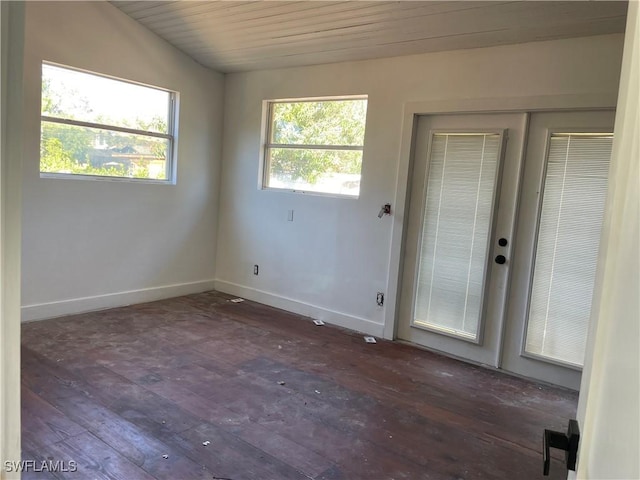 spare room featuring dark hardwood / wood-style flooring and lofted ceiling