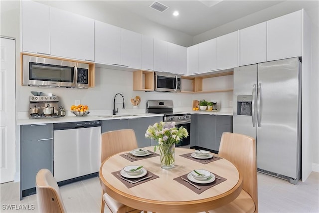 kitchen with gray cabinets, white cabinetry, stainless steel appliances, and light countertops