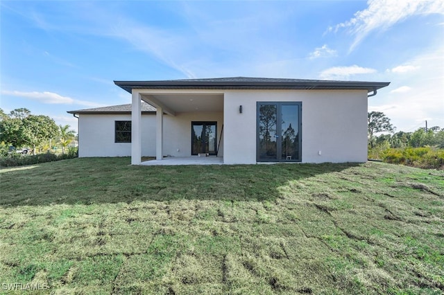 rear view of house with a patio area, stucco siding, and a yard