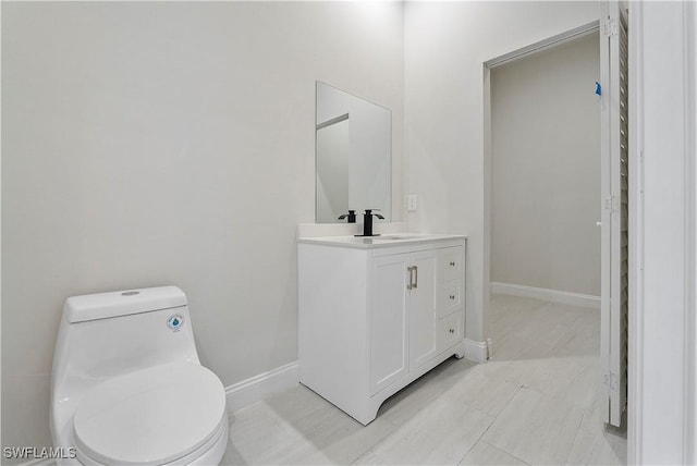 bathroom featuring toilet, baseboards, and vanity