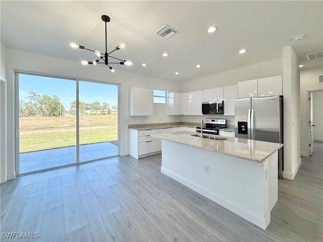 kitchen with white cabinetry, appliances with stainless steel finishes, decorative light fixtures, and sink