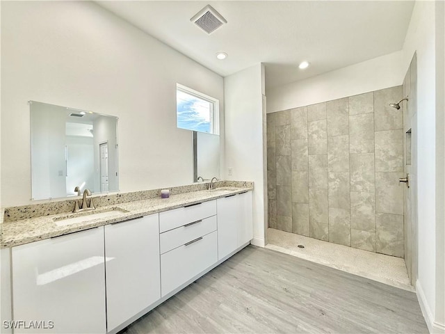 bathroom with hardwood / wood-style flooring, vanity, and a tile shower