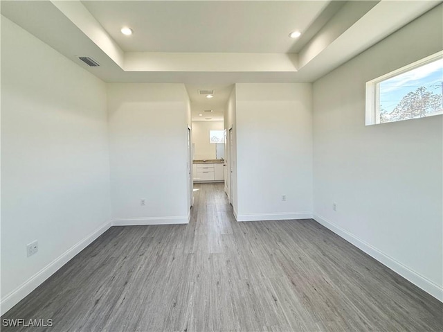 empty room with hardwood / wood-style flooring and a tray ceiling