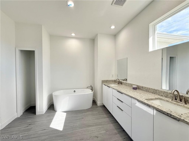 bathroom with vanity, a tub to relax in, and wood-type flooring