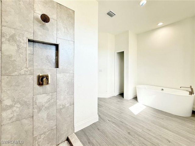 bathroom featuring plus walk in shower and hardwood / wood-style floors