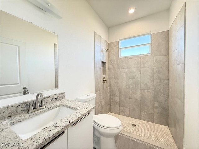 bathroom featuring vanity, toilet, and tiled shower